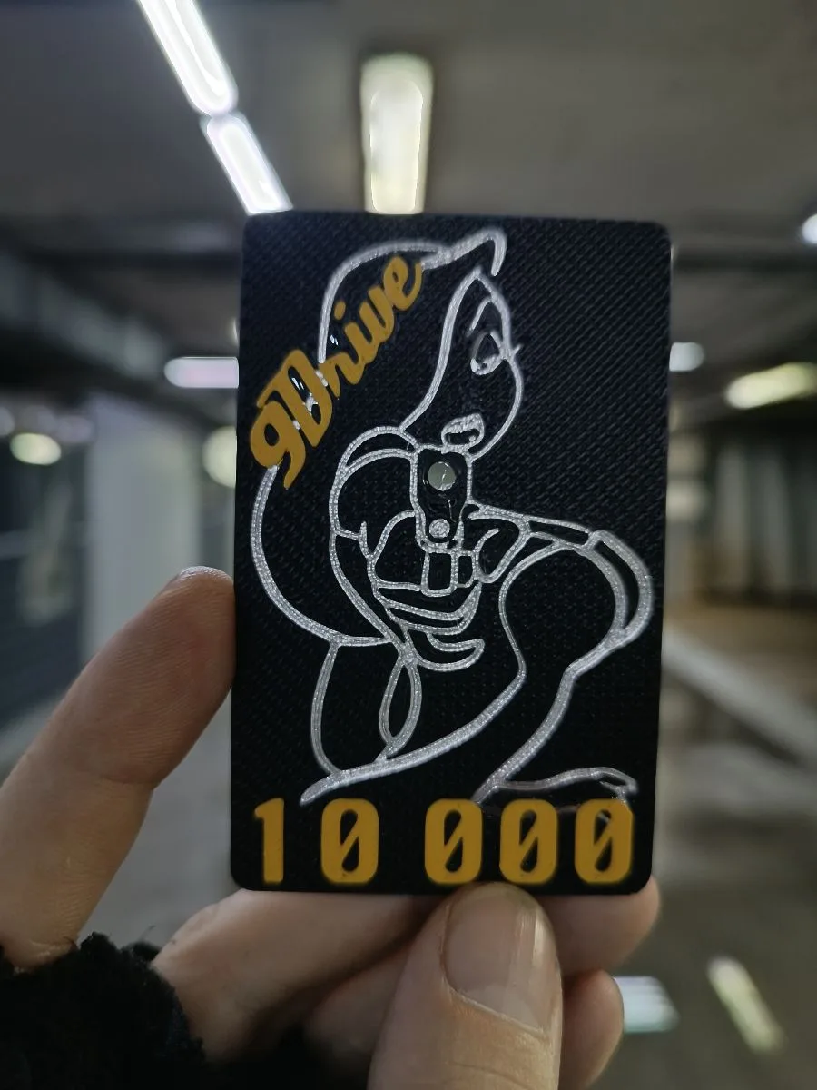 Чёрная карточка 9Drive с золотым логотипом и надписью 10 000 в руке