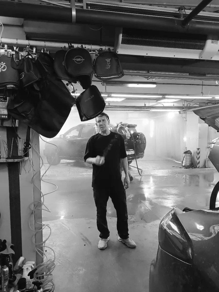 Мастер в моечной зоне ателье, рядом висят подголовники с логотипами Opel и Nissan